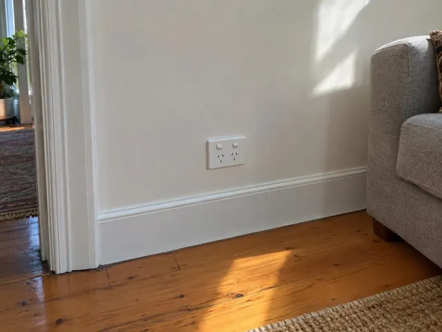 New double power point on a painted wall above skirting in a timber-floored living room in Petersham