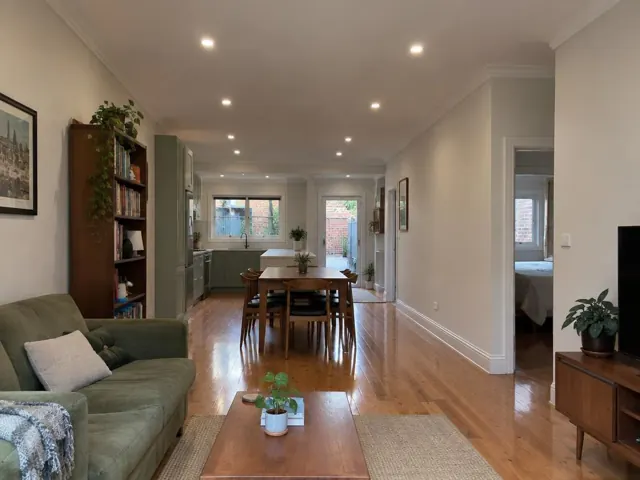 Living and dining room with recessed downlights, timber floors and white walls in Marrickville